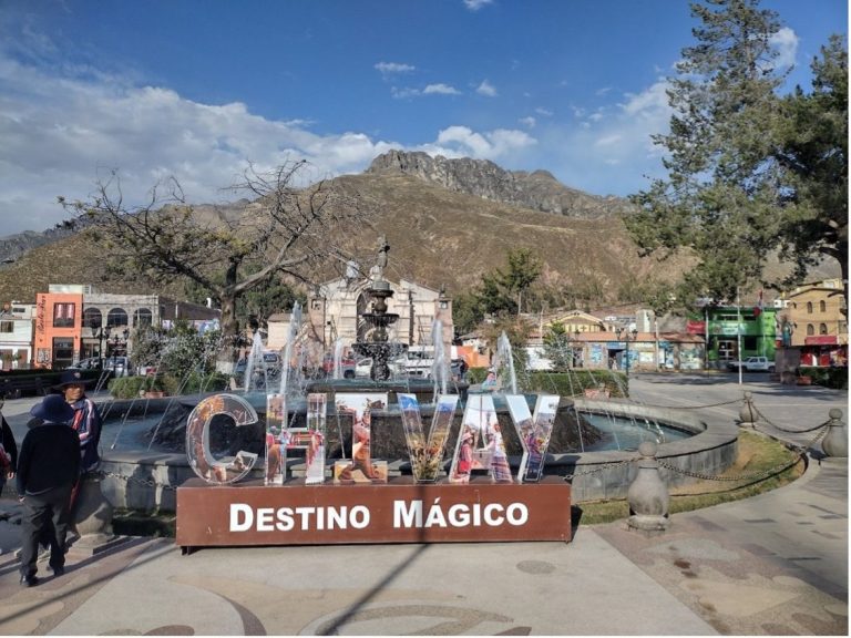 Fountain with "Chitvay Destino Mágico" sign in a scenic plaza with mountains in the background.