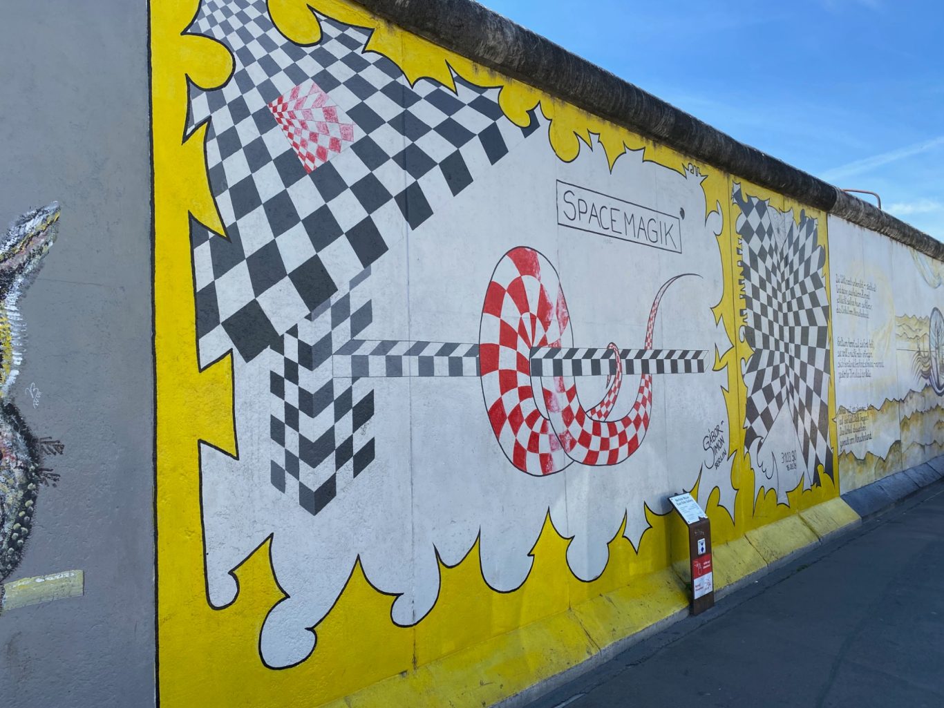 Space Magik Colourful mural featuring abstract patterns in red, black, and yellow on a wall.