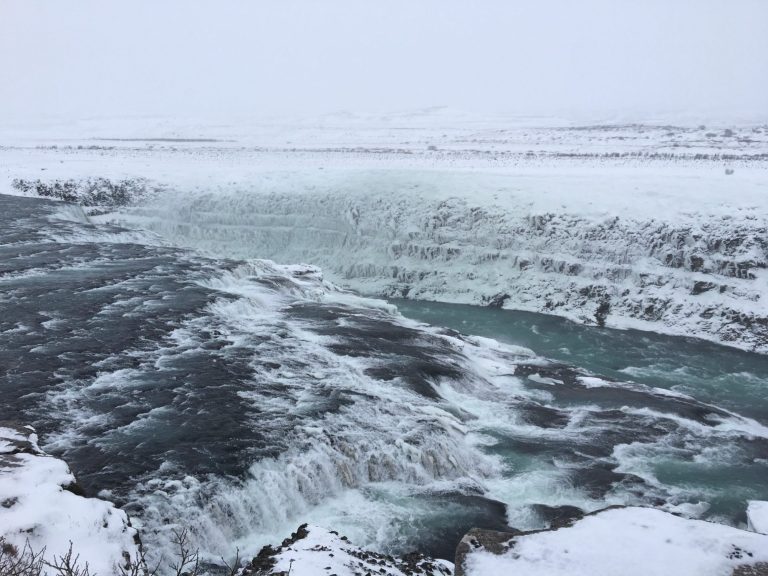Snowy landscape with a turbulent river and icy cliffs.