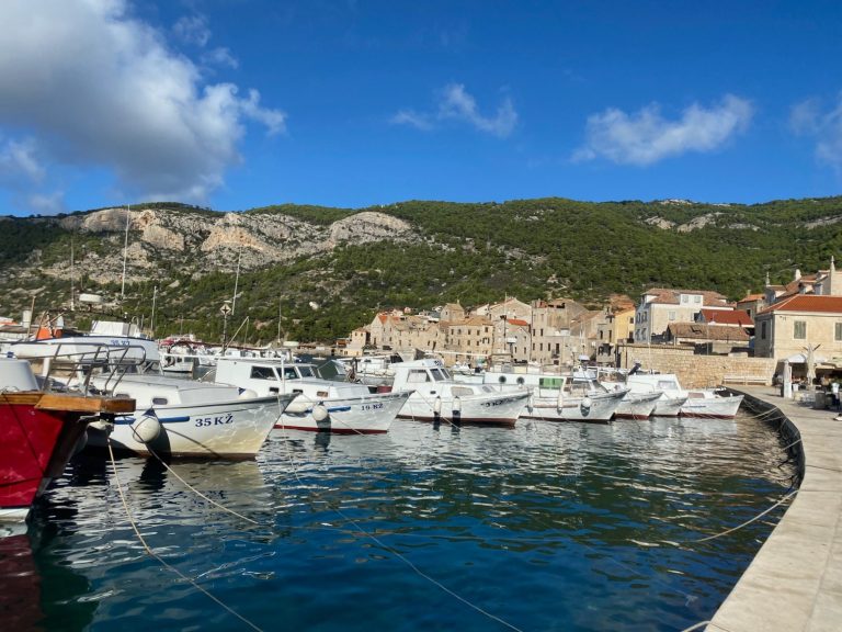 Komiza Harbour Boats moored in a tranquil harbour with rocky hills in the background.