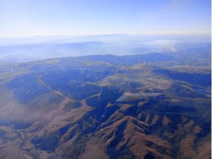 Aerial view of rolling hills and valleys under a clear blue sky.