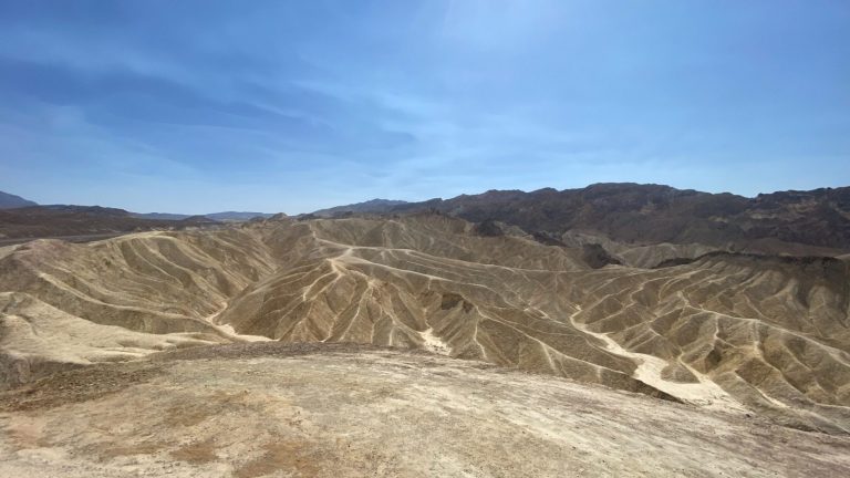 Arid landscape with layered hills and blue sky in the background.