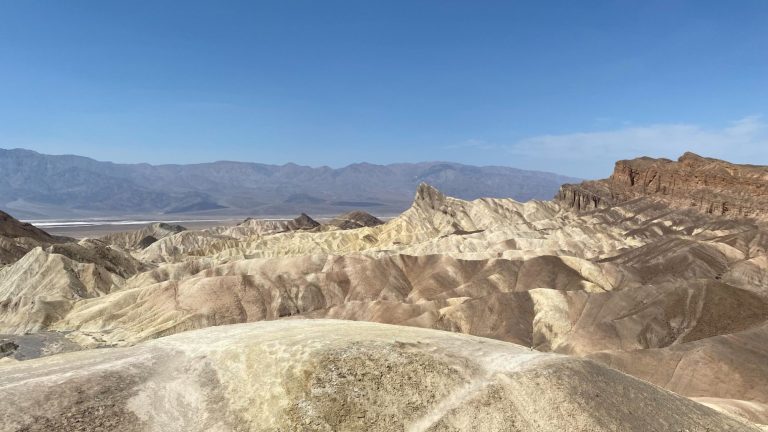 Vast sandy landscape with rugged hills under a clear blue sky.