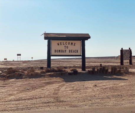 Welcome sign for Burnt Beach in a barren landscape.
