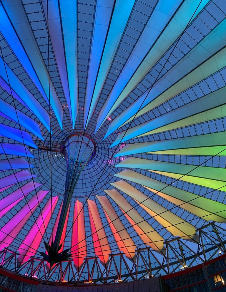 Canopy at Potsdamer Plaz Vibrant, multicoloured ceiling with radiating patterns and a central support structure.