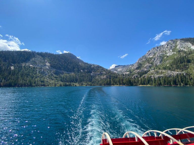 Scenic lake view with mountains and clear blue sky, featuring boat wake.