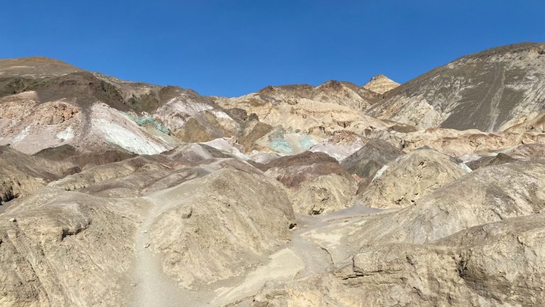 Cliffs with multicoloured mineral deposits under a clear blue sky.
