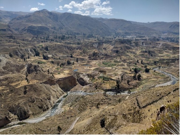 A sweeping view of valleys and a river winding through a mountainous landscape.