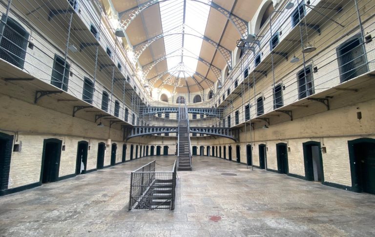 Interior of an empty, historic prison with multiple cell doors and a central staircase.