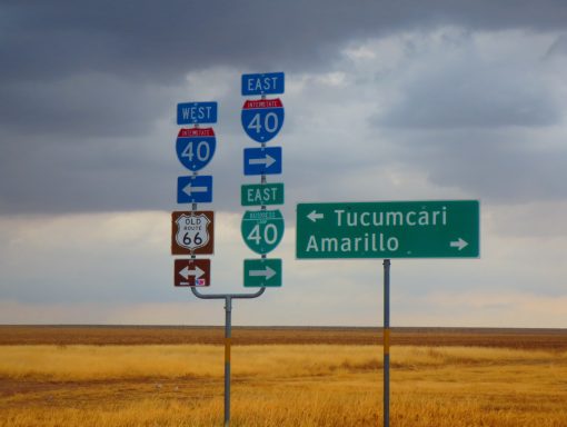 Road signs indicating directions to Tucumcari and Amarillo, with a cloudy sky.