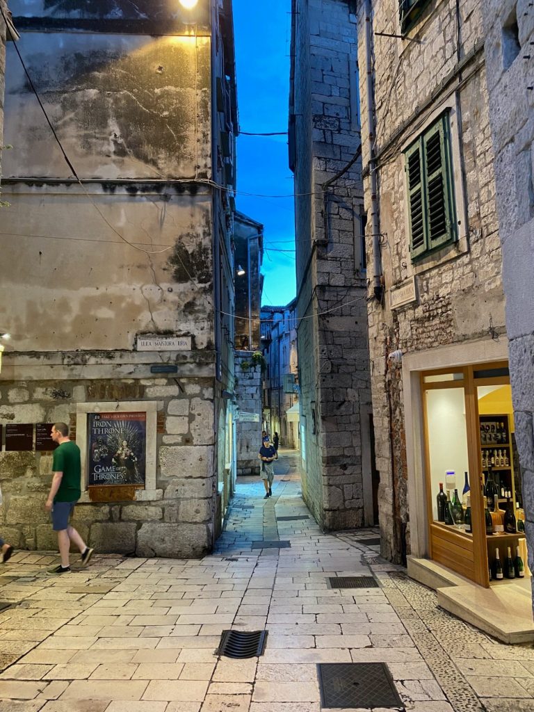 Street of the Old Town Narrow cobbled street lined with stone buildings, illuminated by soft evening light.