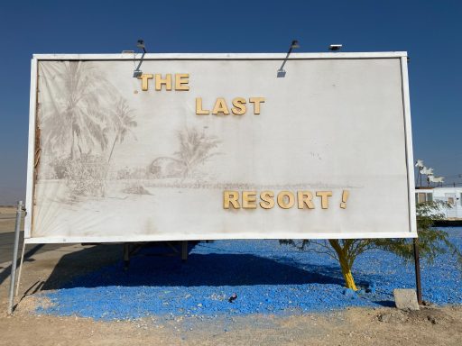 Sign reading "THE LAST RESORT!" with a faded background and blue ground.