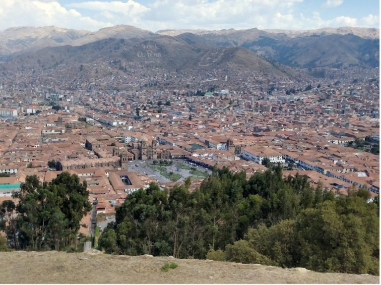 Panoramic view of Cusco, Peru, with terracotta rooftops and surrounding mountains.