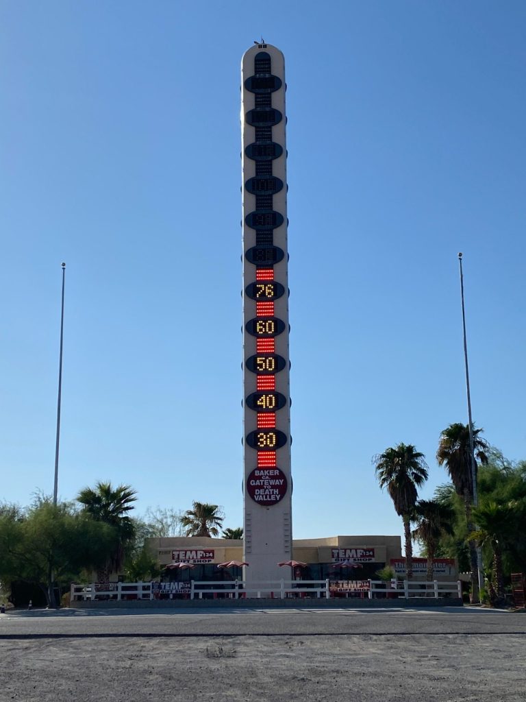 Tall, vertical sign with bright lights and a clear blue sky in the background.