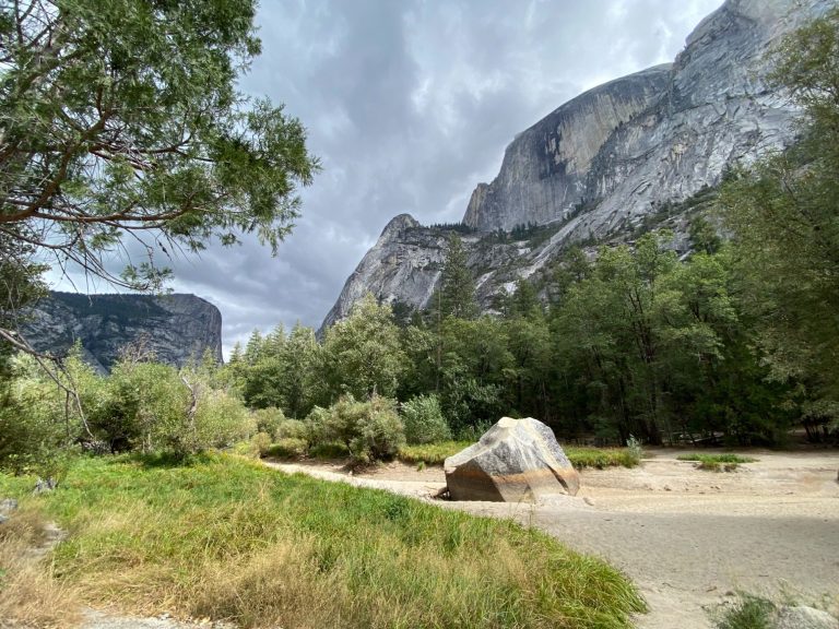 Scenic landscape featuring towering cliffs, lush greenery, and a rocky area.