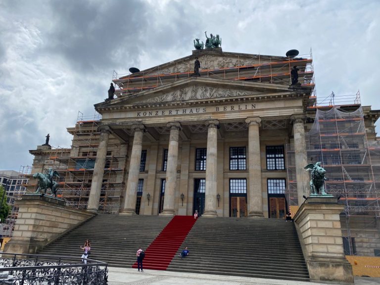 Konzerthaus Grand building with columns, red carpet, and construction scaffolding in the background.