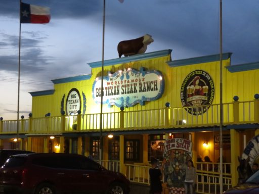 Brightly coloured restaurant exterior with a bull statue on the roof and flag in the background.