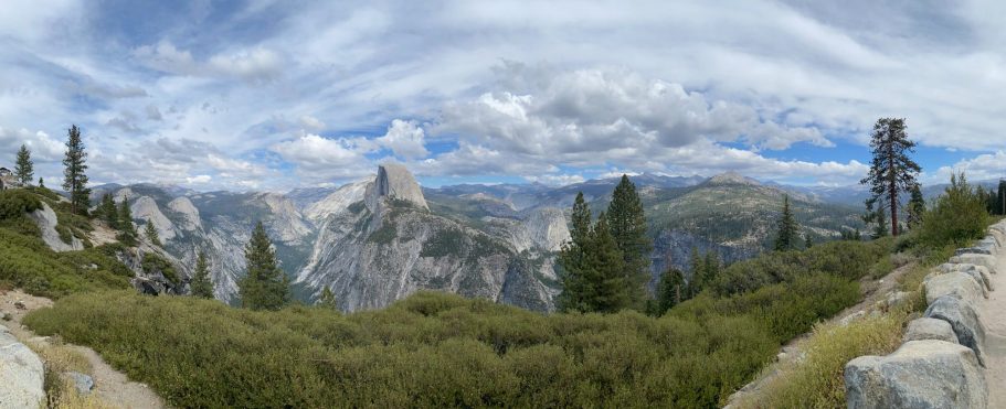 Panoramic view of mountainous landscape with green vegetation and cloudy sky.