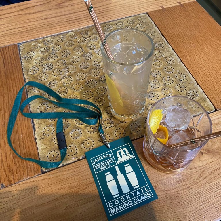 Two drinks on a table, one with a lemon slice and a name tag nearby.