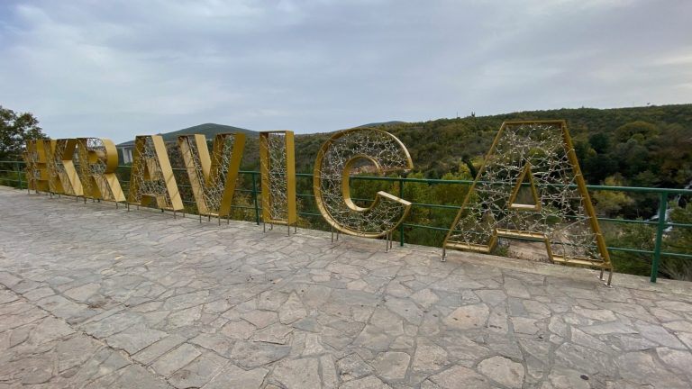 Kravica sign overlooking the falls Large decorative letters spelling "KRAVICA" against a scenic background.