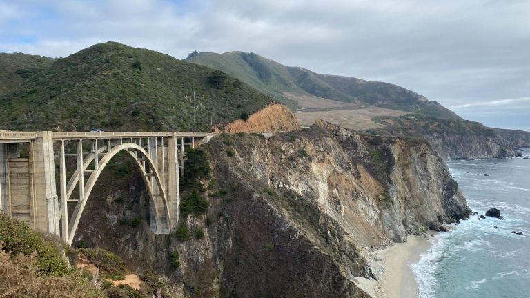 A scenic coastal bridge spanning a cliffside with rolling waves below.