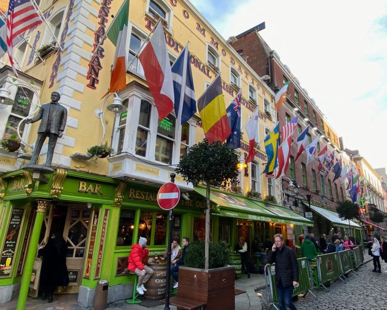 A lively street scene featuring a pub adorned with numerous national flags.