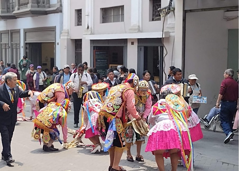 People in traditional costumes performing in a street during a festive celebration.