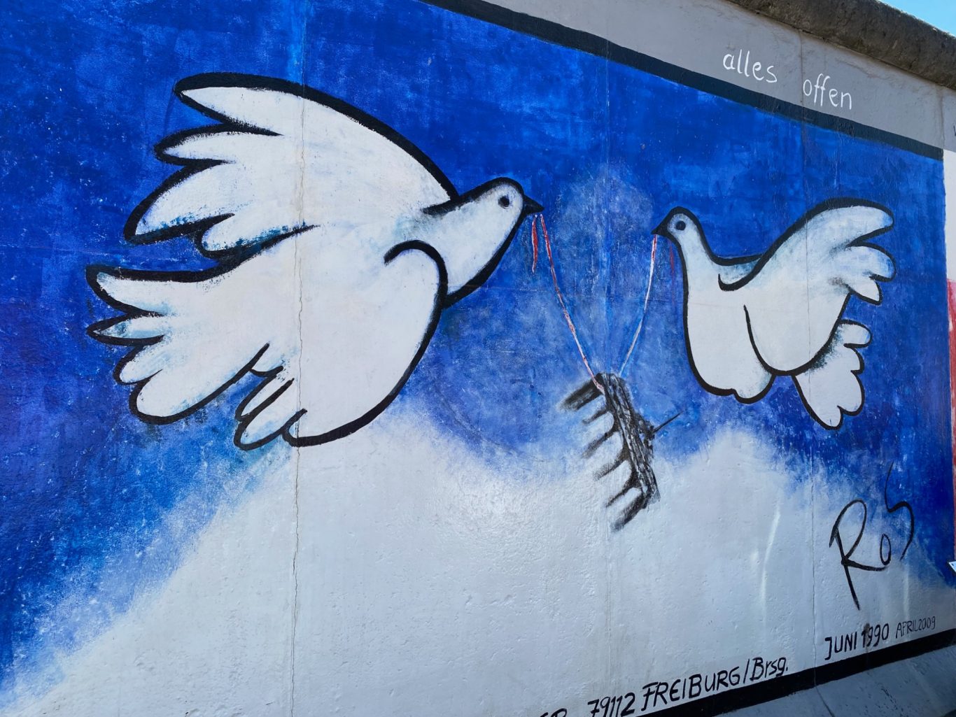 Alles offen (Everything is open) Two white doves flying against a blue background, with a zebra hanging from a string.