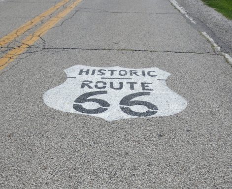 Historic Route 66 sign painted on asphalt road surface.