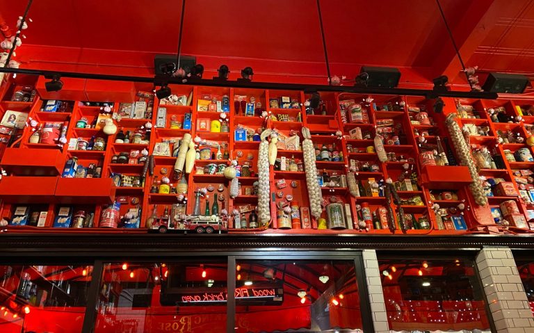 Bright red wall filled with various shelves displaying colourful cans and decor items.