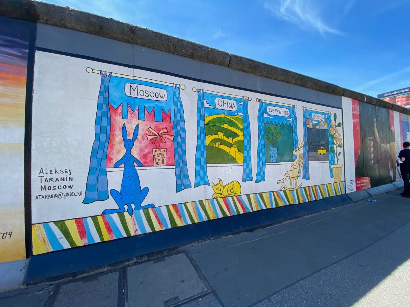 Mauern international (Walls International) Mural featuring curtains and whimsical animal silhouettes on a bright blue sky background.