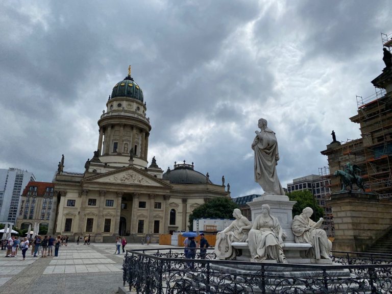 Deutscher Dom Historical building with a dome, surrounded by sculptures and a cloudy sky.