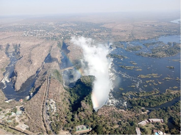 Aerial view of a waterfall surrounded by lush vegetation and a river.