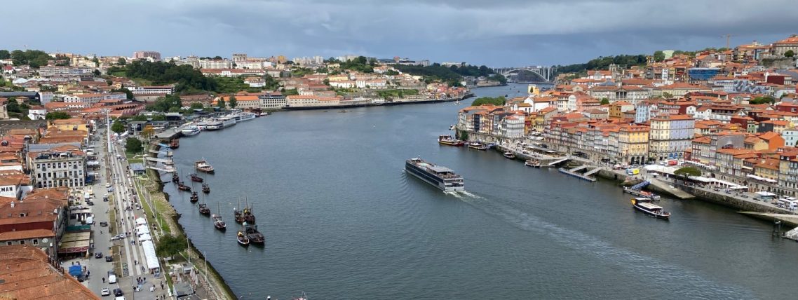 Panoramic view of a river surrounded by colourful buildings and boats along the shore.