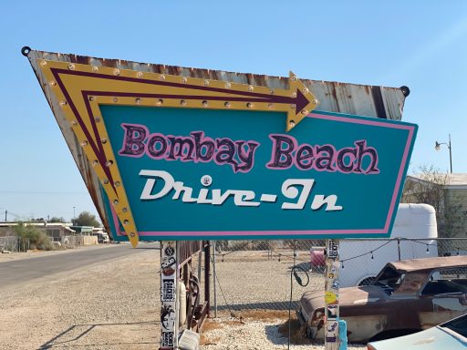 Sign for Bombay Beach Drive-In with colourful retro design and arrow pointing right.
