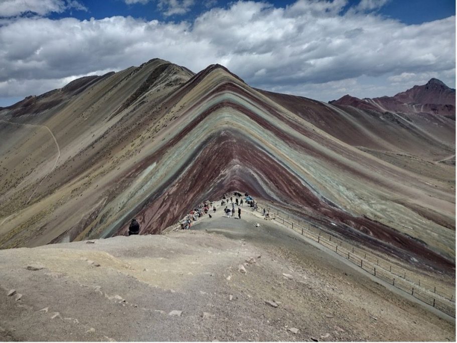 Vibrant, multi-coloured mountain ridge under a cloudy sky.