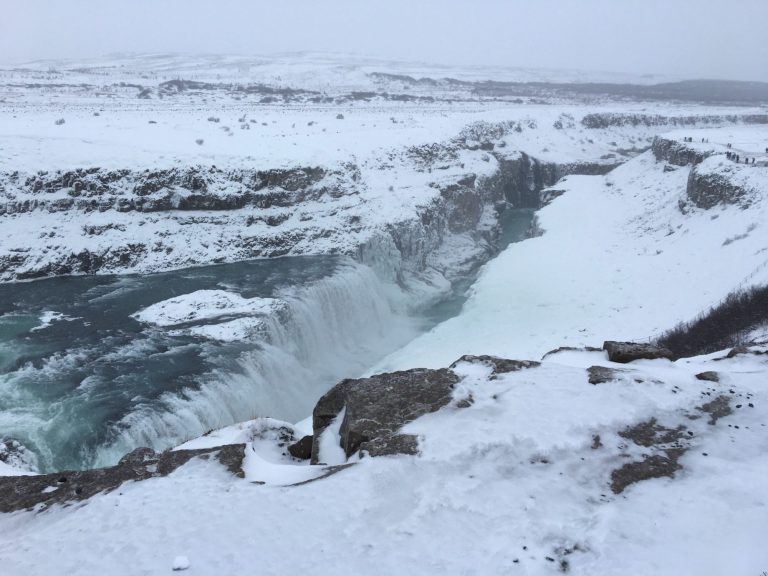 Snow-covered landscape with a powerful waterfall and icy river.